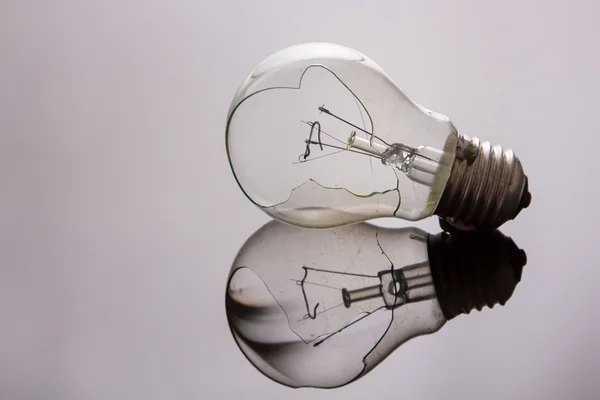 Broken light bulb on shiny surface — Stock Photo, Image