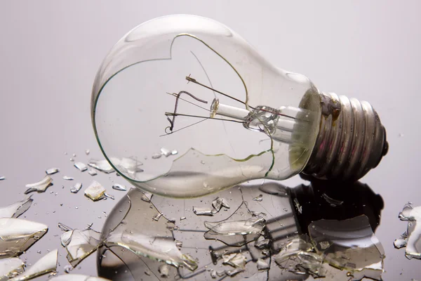 Broken light bulb on shiny surface — Stock Photo, Image