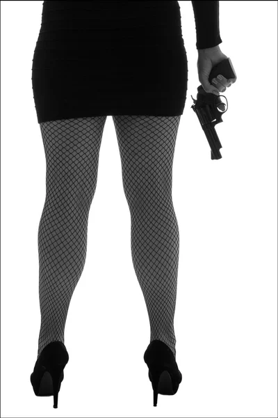 Beine einer gefährlichen Frau mit Handfeuerwaffe und schwarzen Schuhen Silhouette — Stockfoto