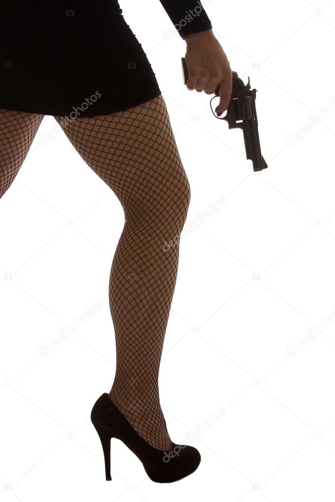 Legs of dangerous woman with handgun and black shoes silhouette