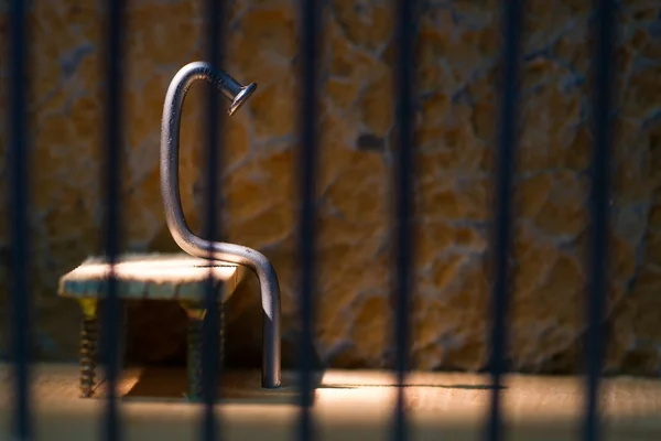 Conceptual jail photo with iron nail sitting behind bars — Stock Photo, Image