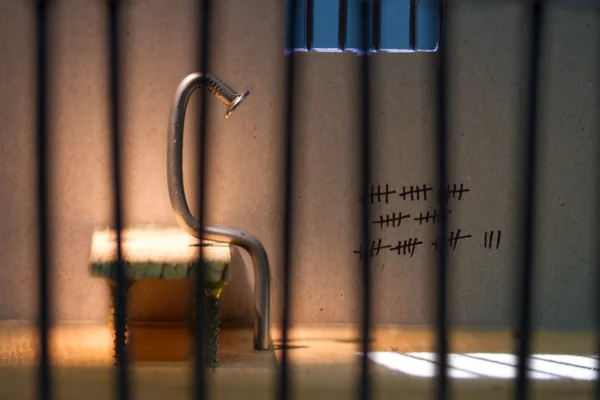 Conceptuele gevangenis foto met ijzeren nagel zitten achter de tralies — Stockfoto