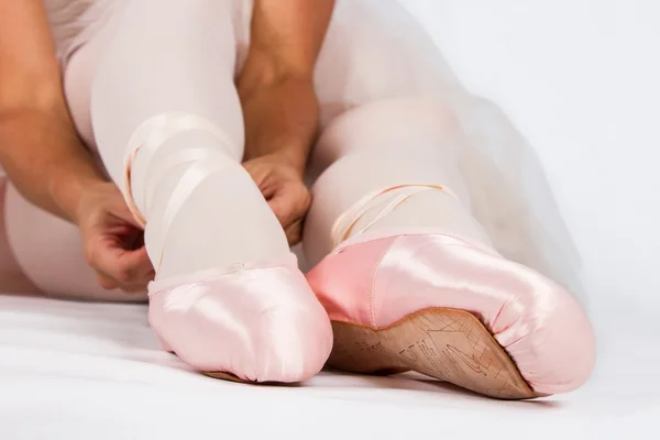 Ballerina setzt sich auf den Boden und zieht Pantoffeln an — Stockfoto