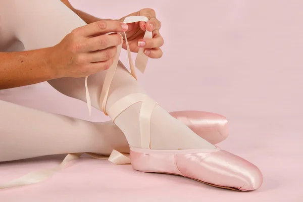 Ballerina setzt sich auf den Boden und zieht Pantoffeln an — Stockfoto