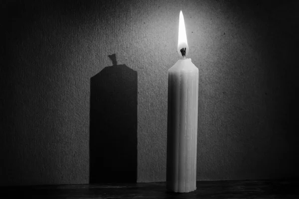 Candle in darkness with spotlight making shadow texture conversi — Stock Photo, Image