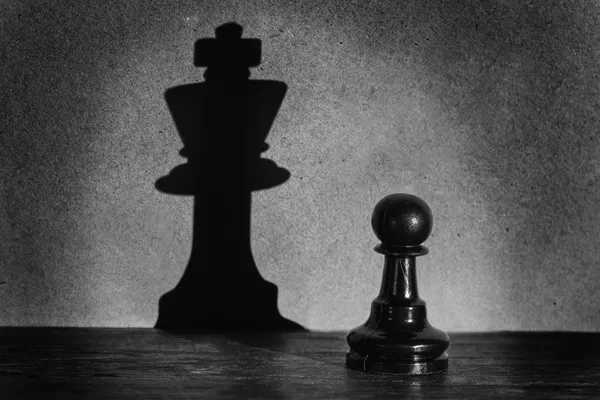 Chess pawn staande in een middelpunt van de belangstelling die een schaduw actistic maken — Stockfoto