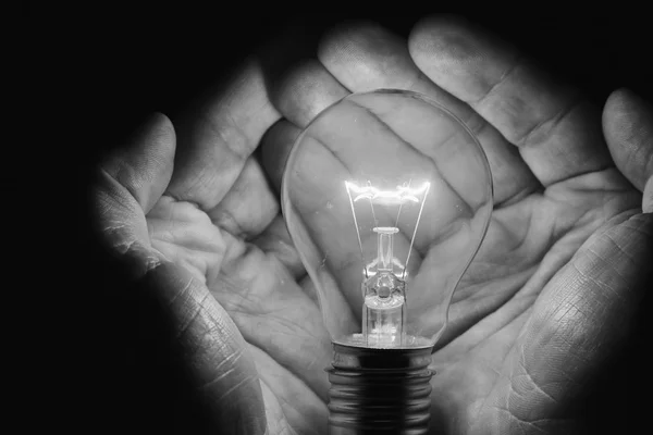 Lidské ruce držící žárovky šetří energii tmy umění — Stock fotografie