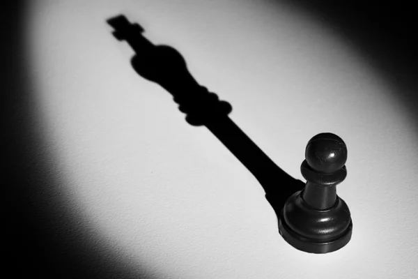 Chess pawn staande in een middelpunt van de belangstelling die een schaduw actistic maken — Stockfoto