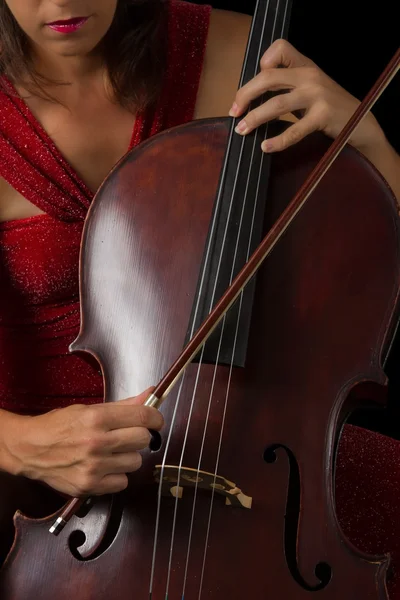 Bella bruna che suona il violoncello con luce selettiva in dre rosso — Foto Stock