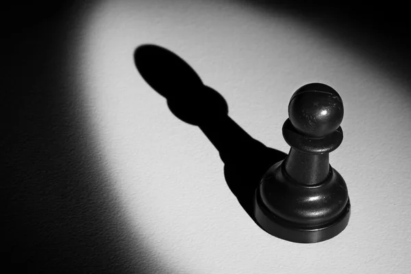 Шахматная пешка, стоящая в центре внимания, что делает тень — стоковое фото