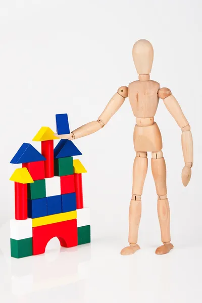 Petit mannequin en bois debout construction blocs colorés isolés sur — Photo