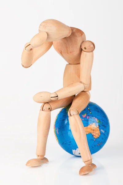 Manequim de madeira sentado em cima de um globo mundial para proteger isolat — Fotografia de Stock
