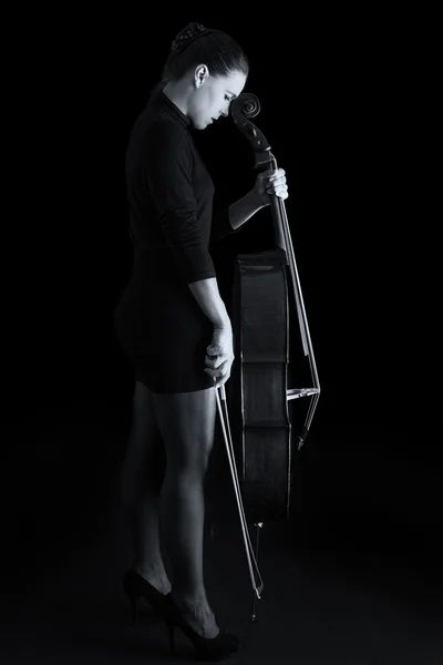 Beautiful brunette holding cello with selective light in red dre — Stock Photo, Image