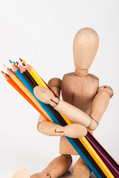 Petit mannequin en bois assis avec un bouquet de crayon de couleur isoler — Photo