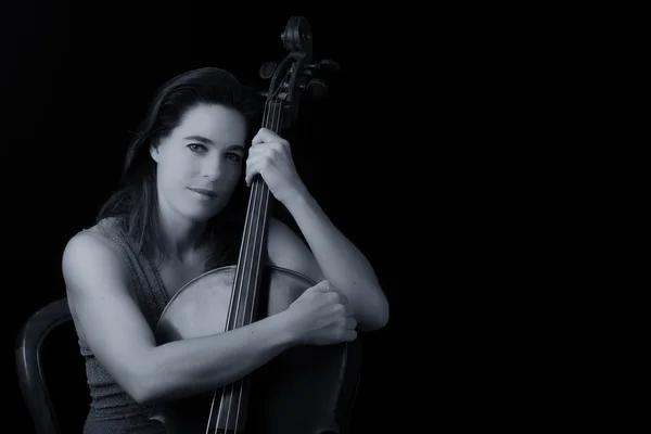 Beautiful brunette holding cello with selective light in red dre — Stock Photo, Image