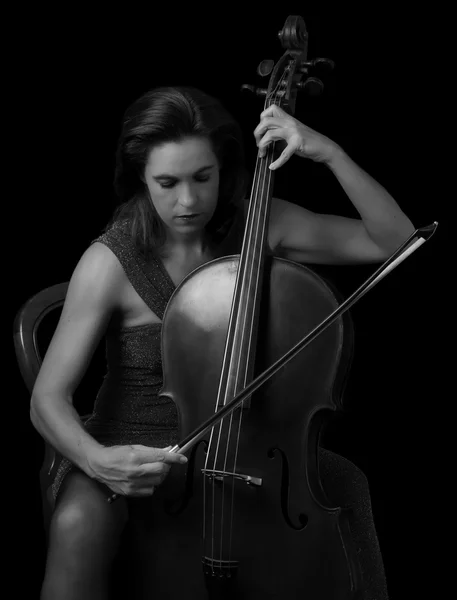 Piękna brunetka gra na wiolonczeli selektywne światło w czerwony dre — Zdjęcie stockowe