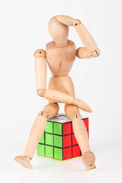 Zmatený dřevěný manekýn sedět na kostky puzzle zmatený po řešení soustav — Stock fotografie