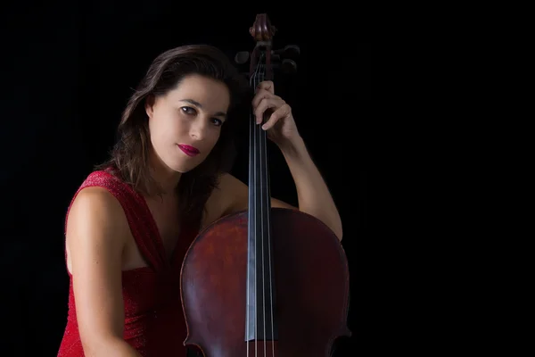 Bella bruna che suona il violoncello con luce selettiva in dre rosso — Foto Stock