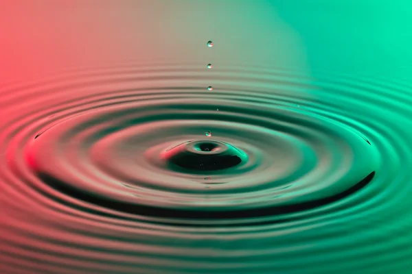 Water drop close up with concentric ripples colourful red and gr — Stock Photo, Image