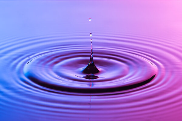 Капля воды близко с концентрической рябью красочный синий и р
