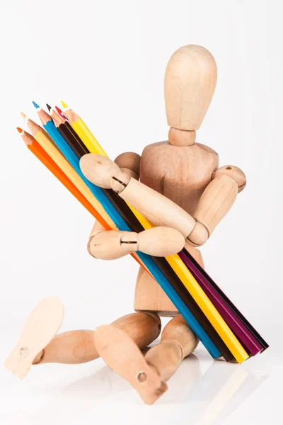 Petit mannequin en bois assis avec un bouquet de crayon de couleur isoler — Photo
