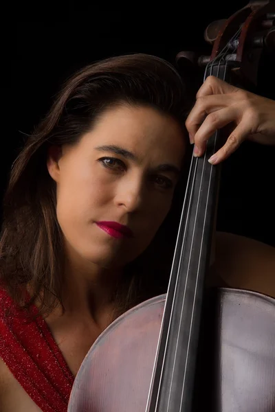 Belle brune jouant du violoncelle avec lumière sélective en dre rouge — Photo