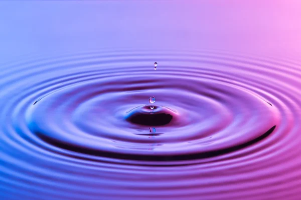 Su damlası yakın up konsantrik ile renkli mavi ve p ripples — Stok fotoğraf