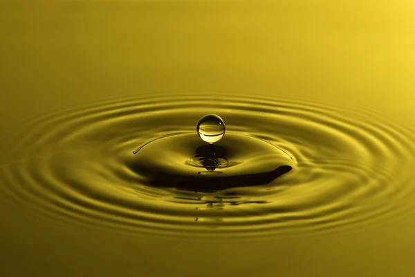 Gota de água perto com ondulações concêntricas colorido amarelo sur — Fotografia de Stock