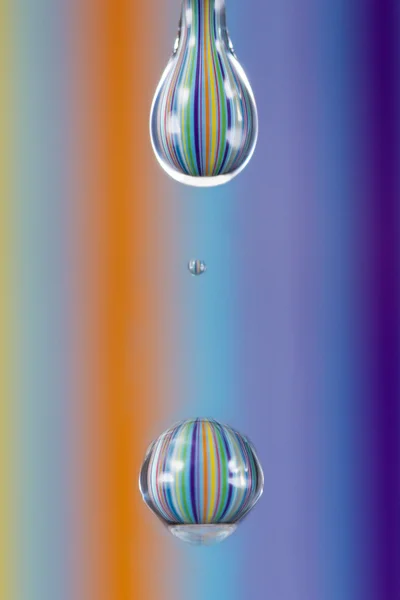 Kropli wody z kolorowymi paskami odbijającym się od tła m — Zdjęcie stockowe