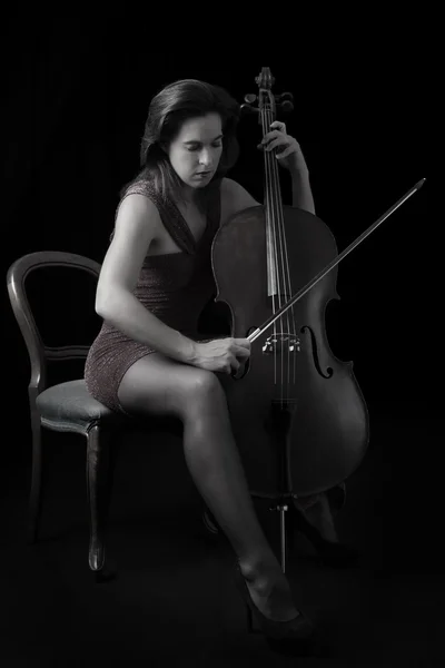 Piękna brunetka gra na wiolonczeli selektywne światło w czerwony dre — Zdjęcie stockowe