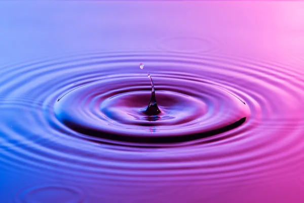 Gota de agua de cerca con ondas concéntricas de color azul y p —  Fotos de Stock