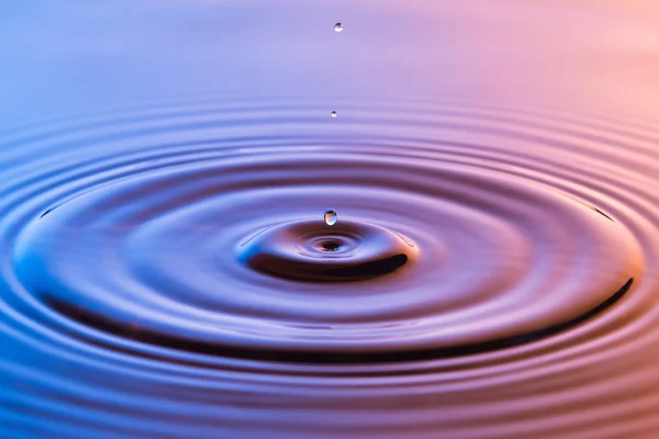 Wassertropfen aus nächster Nähe mit konzentrischen Wellen in buntem Blau und einem — Stockfoto