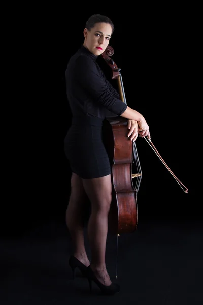 Linda morena segurando violoncelo com luz seletiva em preto d — Fotografia de Stock