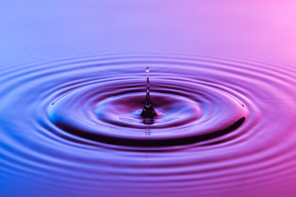 Капля воды близко с концентрической рябью красочный синий и р
