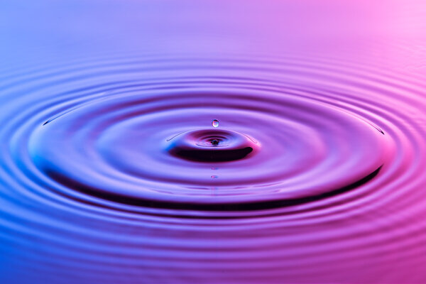 Капля воды близко с концентрической рябью красочный синий и р

