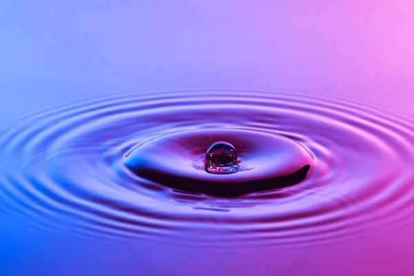 Gota de água perto com ondulações concêntricas colorido azul e p — Fotografia de Stock