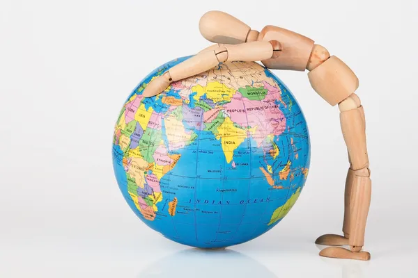 Brown wood mannequin holding concerned a globe protect — Stock Photo, Image