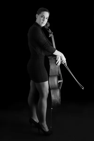 Hermosa morena tocando violonchelo con luz selectiva en d negro — Foto de Stock