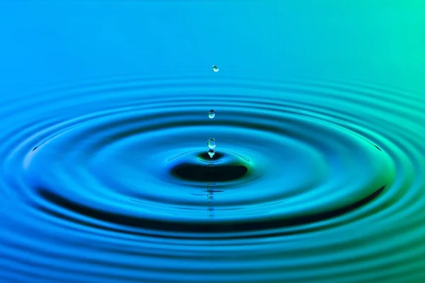 Gota de agua de cerca con ondas concéntricas de color azul y g —  Fotos de Stock