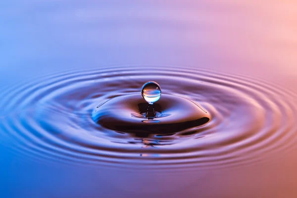 Wassertropfen aus nächster Nähe mit konzentrischen Wellen in buntem Blau und einem — Stockfoto