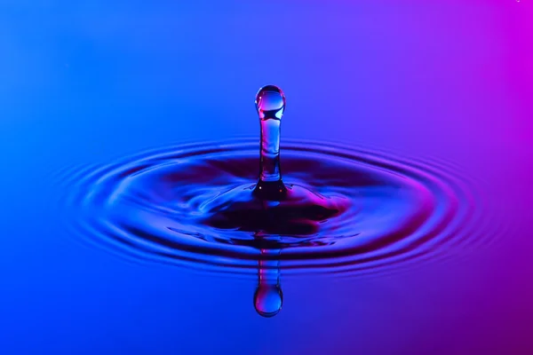 Goutte d'eau de près avec des ondulations concentriques bleu coloré et p — Photo