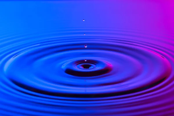 Wassertropfen aus nächster Nähe mit konzentrischen Wellen bunten blau und p — Stockfoto