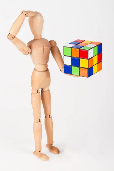 Збентежений дерев'яний манекен тримає кубик головоломки збентежений перед вирішенням — стокове фото