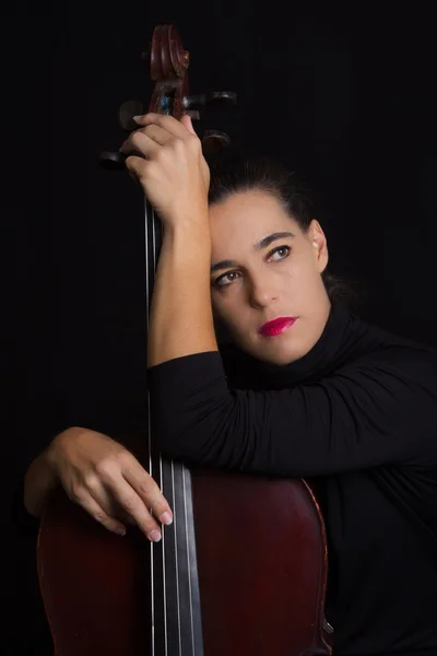 Hermosa morena sosteniendo violonchelo con luz selectiva en d negro — Foto de Stock