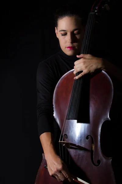 Bella bruna che tiene il violoncello con luce selettiva in nero d — Foto Stock