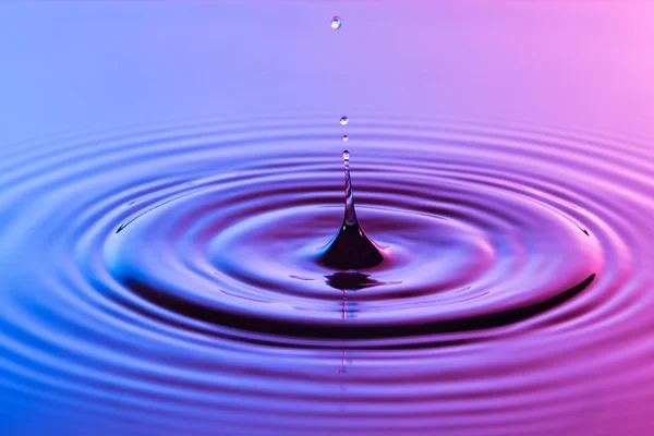 Gota de agua de cerca con ondas concéntricas de color azul y p —  Fotos de Stock