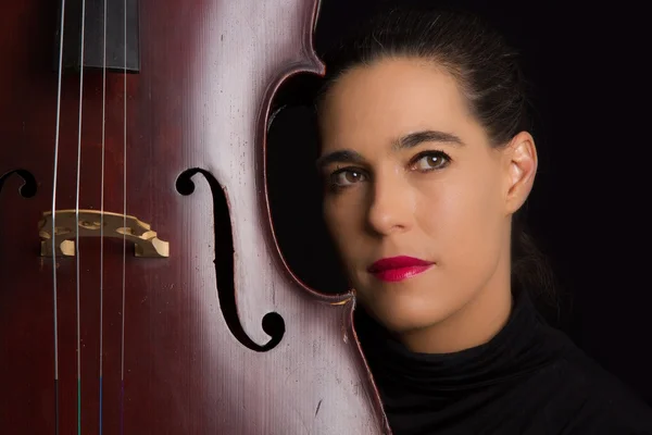 Beautiful brunette holding cello with selective light in black d — Stok Foto