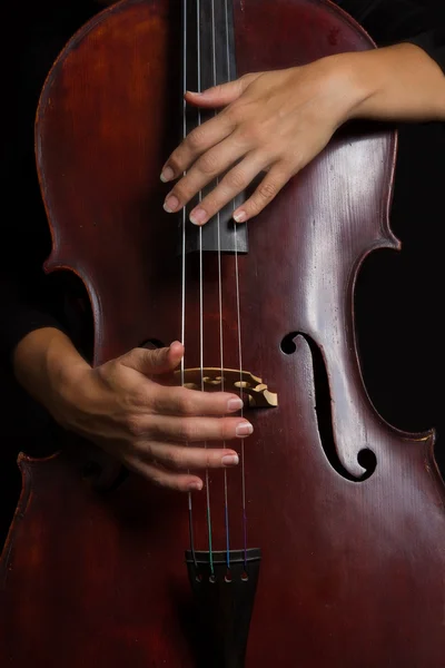 Mulher bonita segurando um violoncelo com luz seletiva e preto d — Fotografia de Stock