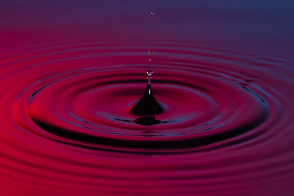 Water drop close up with concentric ripples colourful blue and r — Stock Photo, Image