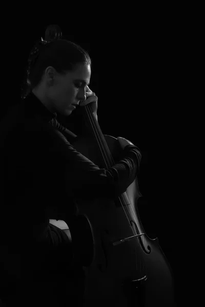 Krásná bruneta hospodářství violoncello s selektivní světlo v červené šaty — Stock fotografie